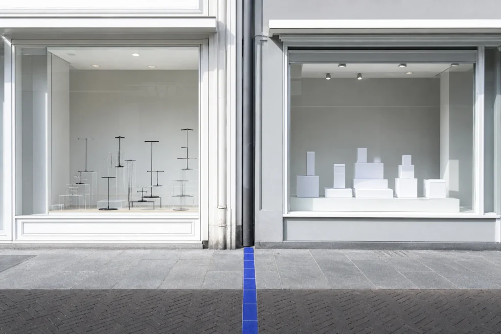 Twee neutrale winkelpuien in Alkmaar met afzonderlijk accessoirehouders en gesloten merkloze productdozen in de etalage.